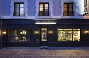 un magasin à l'avant d'un bâtiment avec des lumières dans les fenêtres dans l'établissement Le Nemours Rennes, à Rennes