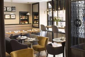 a restaurant with tables and chairs and a window at Le Nemours Rennes in Rennes