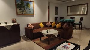 uma sala de estar com um sofá castanho e uma mesa em Plage dès nations 2 bedroom apartment with backyard view em Sidi Bouqnadel