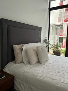 1 cama con almohadas blancas y ventana grande en Apartamento moderno 2 habitaciones y 2 banos area Cayala y Embajada USA CASH ONLY en Guatemala