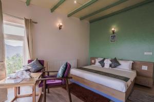 1 dormitorio con cama, mesa y ventana en Adrushya- Suites & Villas by MLS en Mukteswar