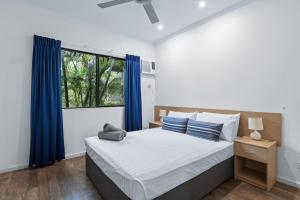 布魯姆的住宿－Cable Beach Apartments，一间卧室配有一张带蓝色窗帘的床和一扇窗户