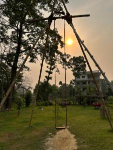 a swing in a park with the sunset in the background at Hotel Riverside with Swimming pool in Sauraha