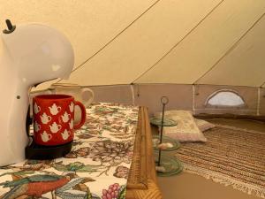 Pädaste Aerga Sunrise Glamping في Pädaste: كوب قهوة احمر جالس على طاولة في خيمة
