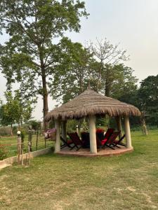 a gazebo with chairs and a straw roof at Hotel Riverside with Swimming pool in Sauraha