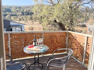 a table and chairs on a balcony with wine glasses at Iron Bark Chalet in Crackenback