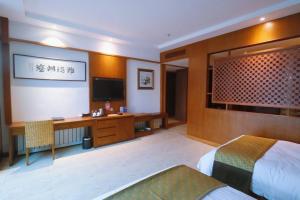 Habitación de hotel con cama y TV en Rainbow Valley Hot Spring Hotel, en Gaizhou