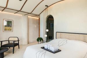 um quarto com uma cama branca e uma cadeira em Oculus Bali em Kintamani