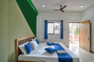 a bedroom with a bed with blue and white pillows at Little Beach Home Stay at Calangute in Calangute