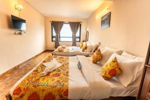a hotel room with two beds and a couch at Muscatel Fairmont – 100 Mts from Mall Road in Darjeeling