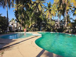 a swimming pool with palm trees in a resort at Casa frente al mar con playa privada Barra de Navidad in Barra de Navidad