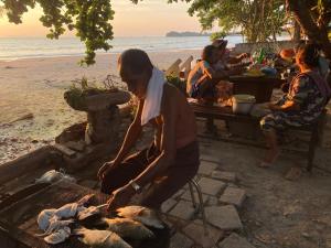 a woman cooking food on a grill on the beach at Coconut Lanta Resort @Klong Dow beach in Krabi