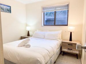 een slaapkamer met een groot wit bed met 2 lampen bij Mowamba E1 in Thredbo