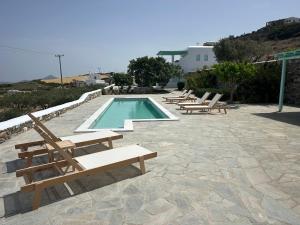 a swimming pool with lounge chairs and a swimming pool at Aegean Queen Villas in Naousa
