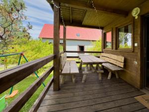a wooden porch with a picnic table and benches on it at Domek nad Jeziorem in Ryn