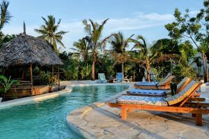 a pool at a resort with chairs and palm trees at Lala Land Lodge in Kizimkazi