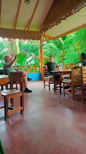 un grupo de personas sentadas en mesas en un restaurante en Orchid Bugalows. en Timbanglawang