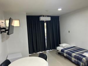 a room with a bed and a table and a window at Hotel Plaza Venezuela in Caracas