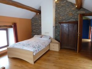 1 dormitorio con cama y pared de piedra en gîte Le cheval ardennais en Gouvy