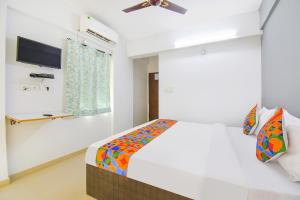 biała sypialnia z łóżkiem i telewizorem z płaskim ekranem w obiekcie FabHotel Happy Stay In w mieście Hinjewadi