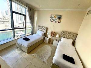 a bedroom with two beds and a large window at Wonderful two bed room with full marina view in Dubai