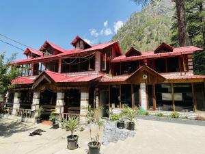 um grande edifício de madeira com uma montanha ao fundo em The Lalits Kitchen em Kasol