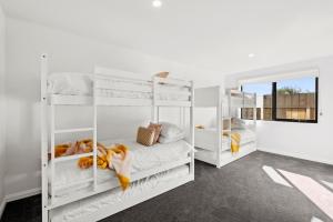 a bedroom with white bunk beds and a mirror at The Absolute Beach Escape For 21 in Saint Leonards