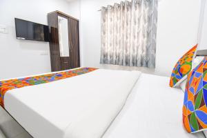 a white bedroom with two beds and a tv at FabHotel Silver 7 Homes in Hinjewadi