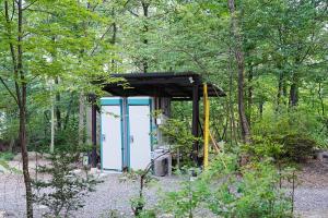 a shed with a blue door in the woods at Glamping Azumino BASE ポレキャン in Aoki-gemi