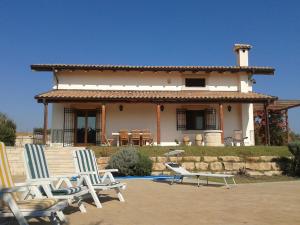 a house with two lawn chairs in front of it at Behara in Marina di Ragusa