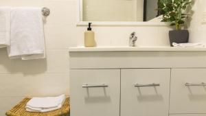 a white bathroom with a sink and a mirror at Gidgets on Gretel in Nelson Bay