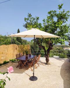 a table with an umbrella next to a bench at Totolos home in Lazaratika Corfu in Áyios Pandeleḯmon