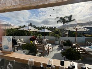 patio ze stołami, krzesłami i parasolami w obiekcie South Seas Motel w mieście Merimbula