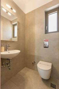 a bathroom with a sink and a toilet and a mirror at Brand New: Kefalonia Stone Villas - Villa Trapezaki Retreat in Trapezaki