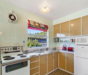 a kitchen with a white stove top oven next to a window at Motuoapa Lakeside Retreat in Turangi +4 photos