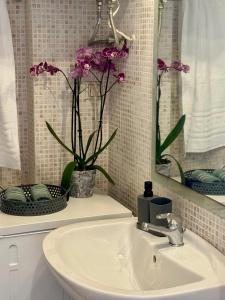 a bathroom with a sink and a mirror and flowers at Dimeli Sea View Apartment in Barbati +9 photos