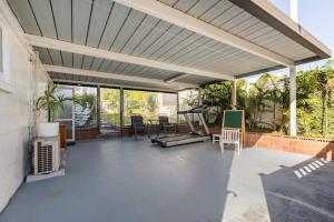 a large covered patio with chairs and a treadmill at Your home at Cockle Bay in Auckland