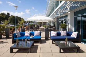 eine Terrasse mit blauen Sofas und Tischen sowie ein Gebäude in der Unterkunft Captain's Club Hotel & Spa in Christchurch