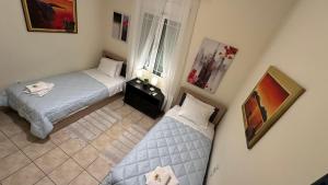 two beds in a small room with paintings on the wall at Patras Centre Apartment in Patra
