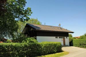 una casa bianca e nera con cespugli e alberi di Birkenwind a Bernau am Chiemsee