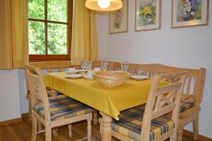 einen Esstisch mit einem gelben Tischtuch und Stühlen in der Unterkunft Ferienresidenz Chiemseestrand - Apartment 14 in Chieming