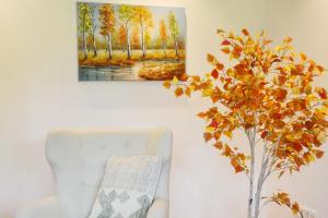 uma pintura pendurada numa parede ao lado de uma cadeira e uma planta em ChiemseeZeit em Gstadt am Chiemsee
