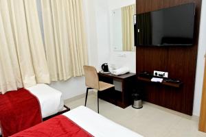 a hotel room with a bed and a desk with a television at The Mallika Sapphire in Chikmagalūr