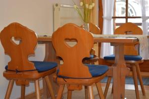 een eettafel met 3 houten stoelen en een tafel bij Ferienresidenz Chiemseestrand - Chiemseesonne in Chieming