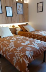 1 Schlafzimmer mit 2 Betten und braunen und weißen Decken in der Unterkunft Gite & Spa Au pommier fleuri et son "Appart" indépendant in Drusenheim