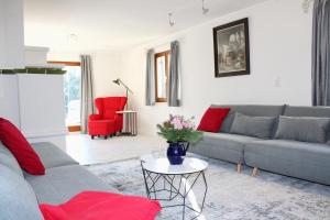 ein Wohnzimmer mit einem grauen Sofa und roten Stühlen in der Unterkunft Landsitz SeeBlick in Bernau am Chiemsee