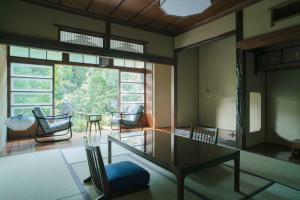 Zimmer mit einem Tisch und Stühlen sowie einem großen Fenster in der Unterkunft Ochiairo in Izu