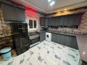 a large kitchen with black cabinets and white appliances at Nubian Villa with Private Pool in Naj‘ al Aḩwāl