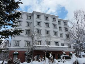 ein weißes Gebäude mit Schnee davor in der Unterkunft Hotel Abest Happo Aldea in Hakuba