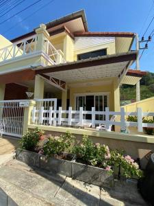 a yellow house with a white fence and some flowers at Kata beach townhouse in Kata Beach